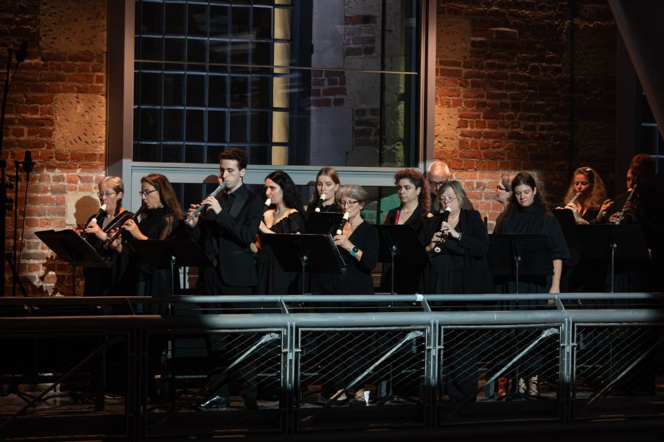  A group of musicians wearing black playing recorders